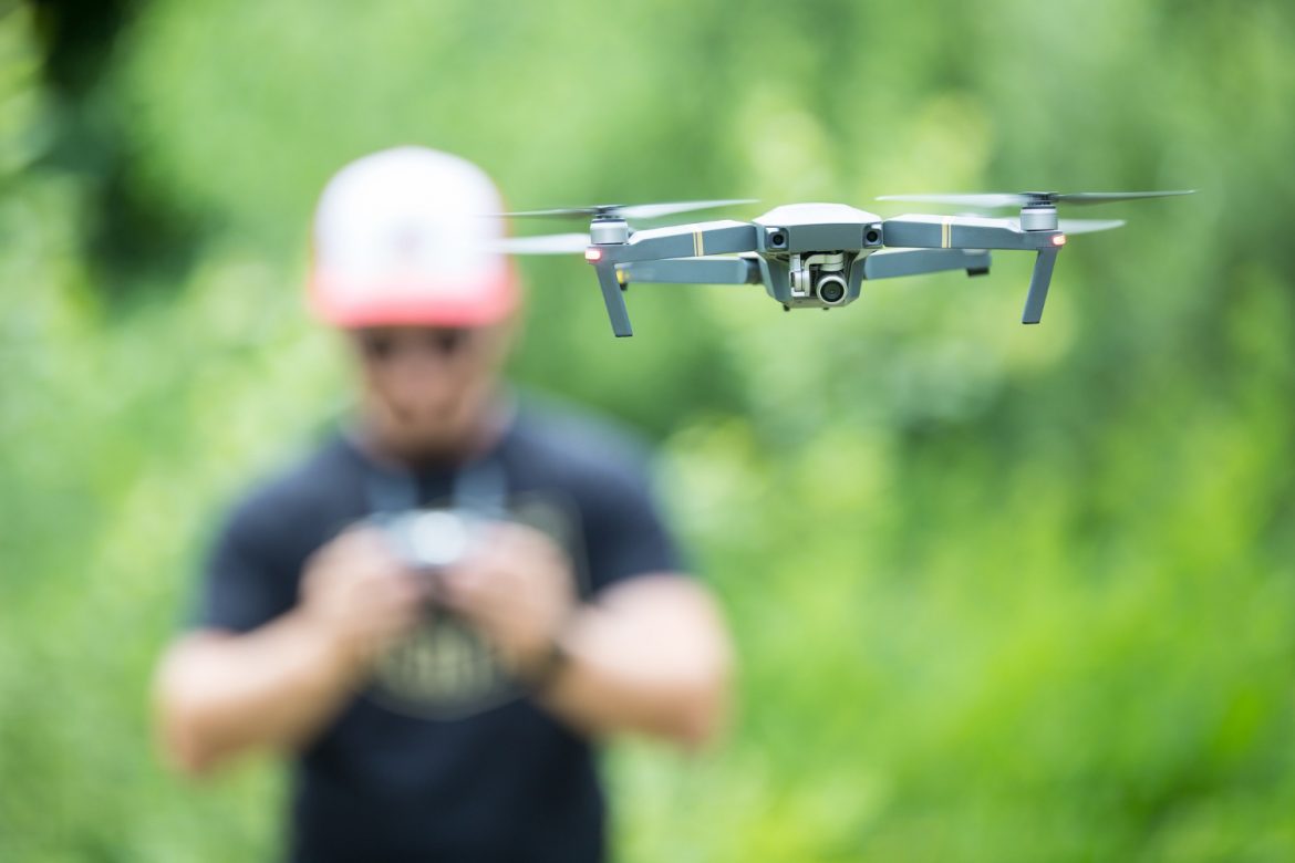 young-man-holding-remote-controller-and-flying-with-drone-in-the-park