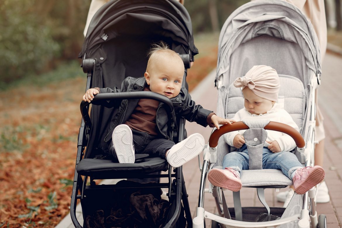 Two young mothers walking in a autumn park with carriages